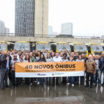 prefeito Orlando Morando ao lado de ônibus novos