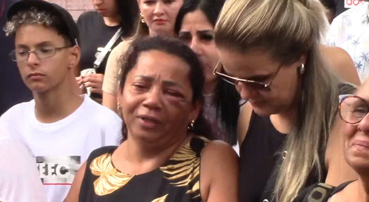 Muito emocionada, mãe é amparada durante enterro da filha.